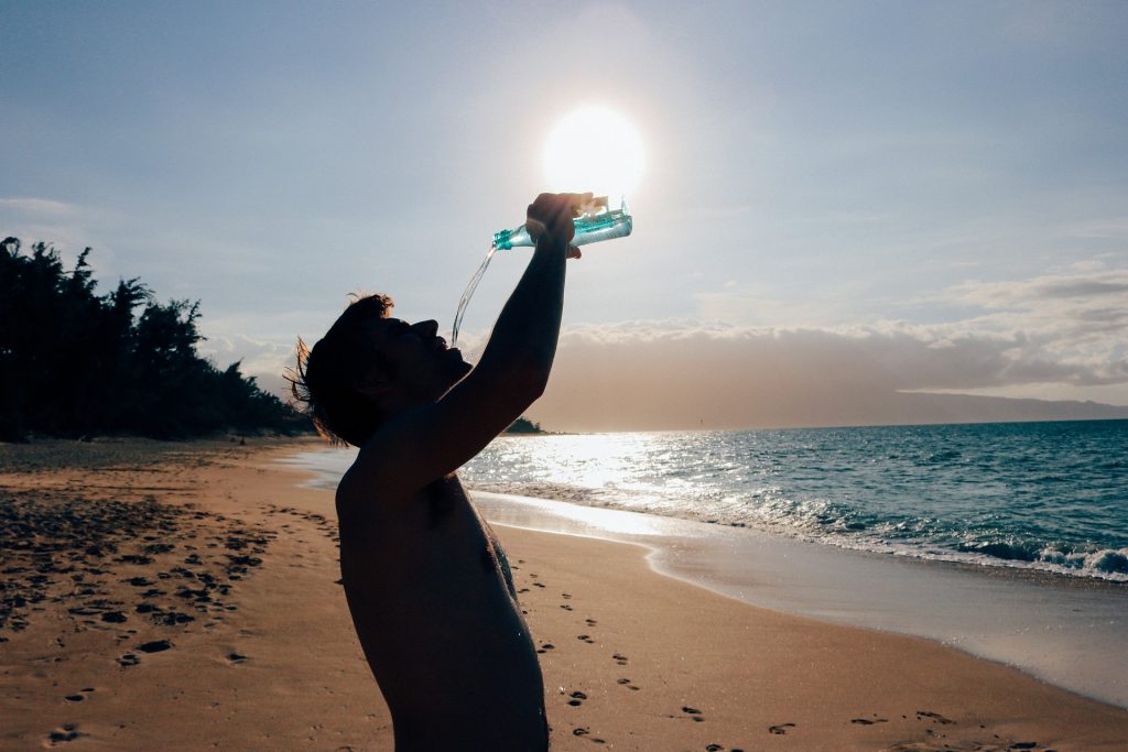 Silhouette of a man drinking bottled water on a beach